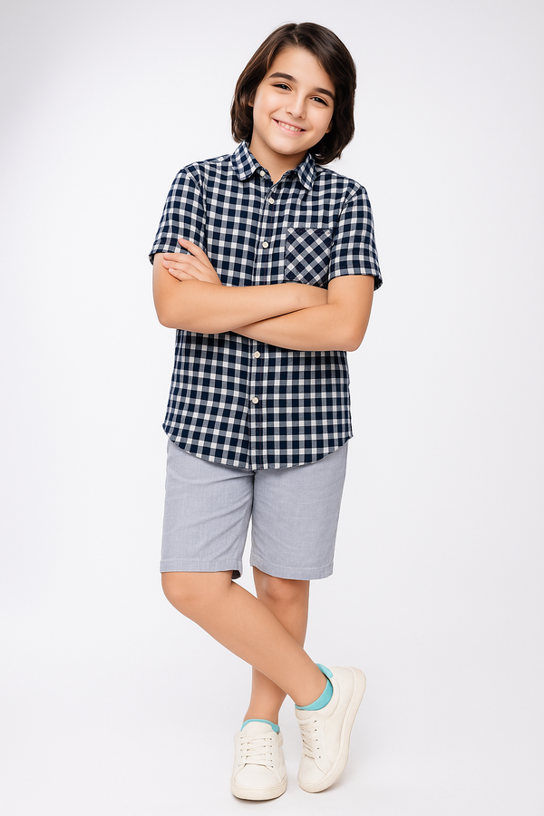Child wearing a checkered shirt and shorts with white sneakers on a light gray background
